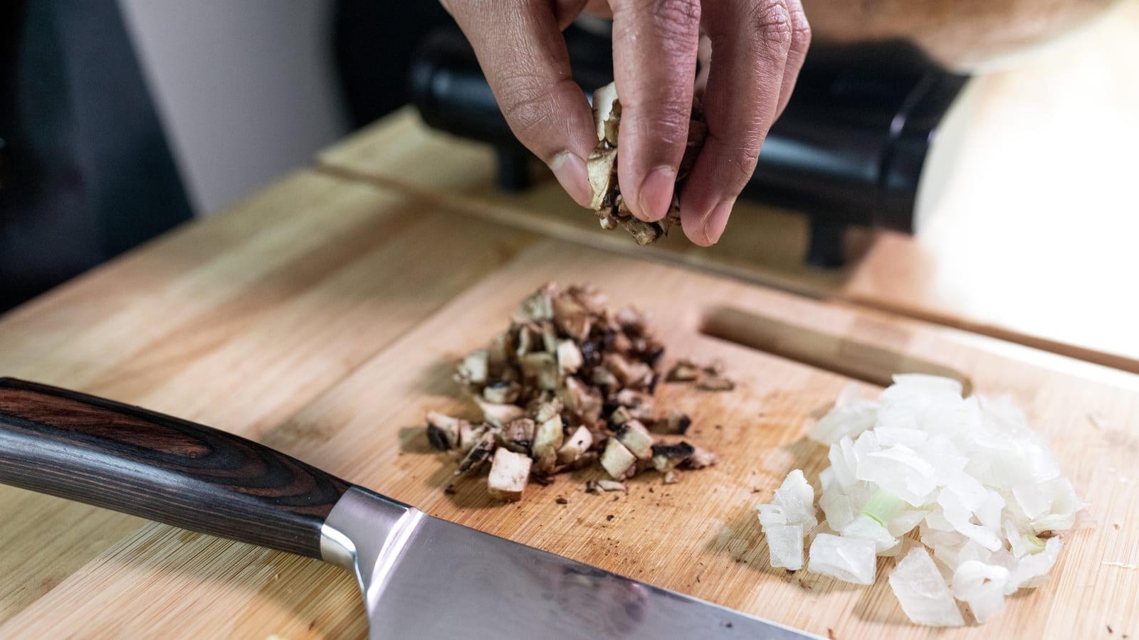 A pair of hands preparing a healthy meal of fresh vegetables on a kitchen counter